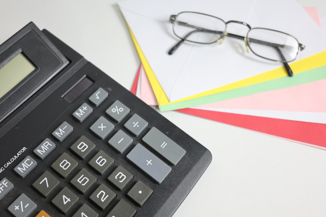 Clean, modern desk setup featuring a laptop, a set of house keys, and a calculator, symbolizing the combination of real es...
