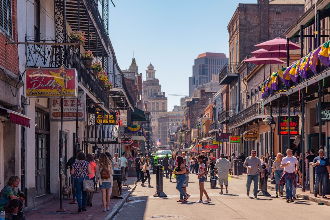 A well-dressed real estate professional confidently walking in front of a building with classic New Orleans architectural details, representing local expertise.